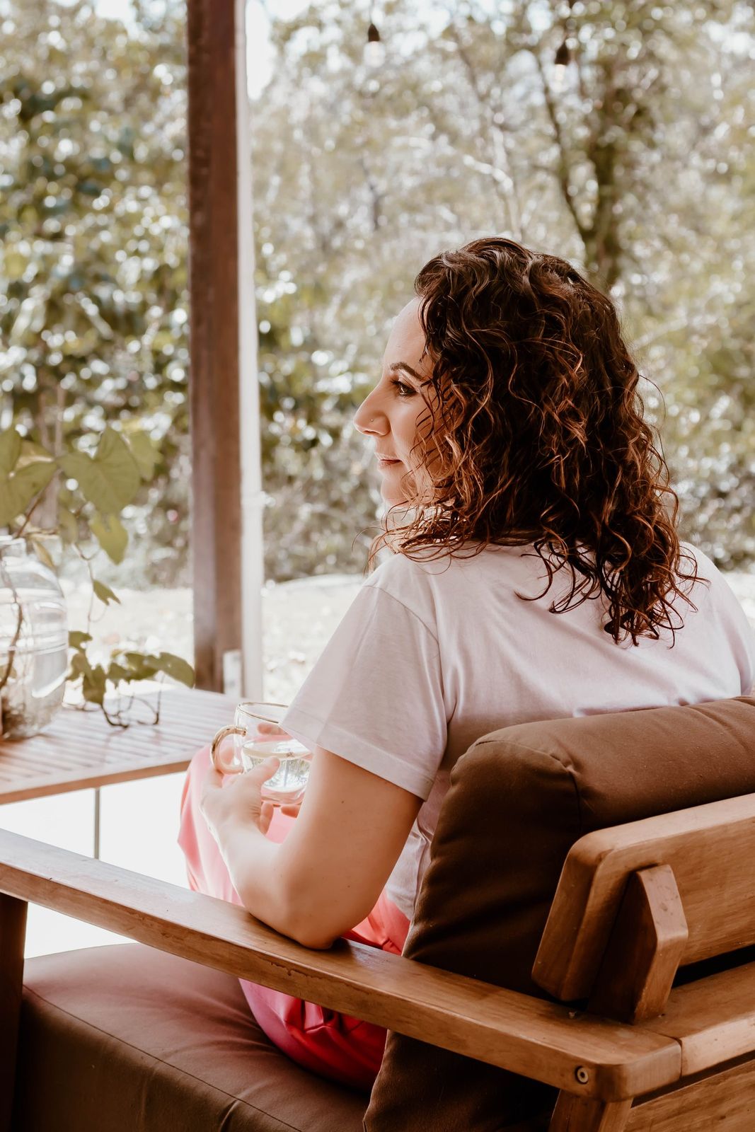 Emma seated with a cup of tea, looking out at the trees